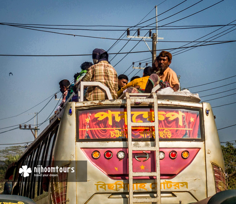 People traveling on the roof of a bus in Bangladesh